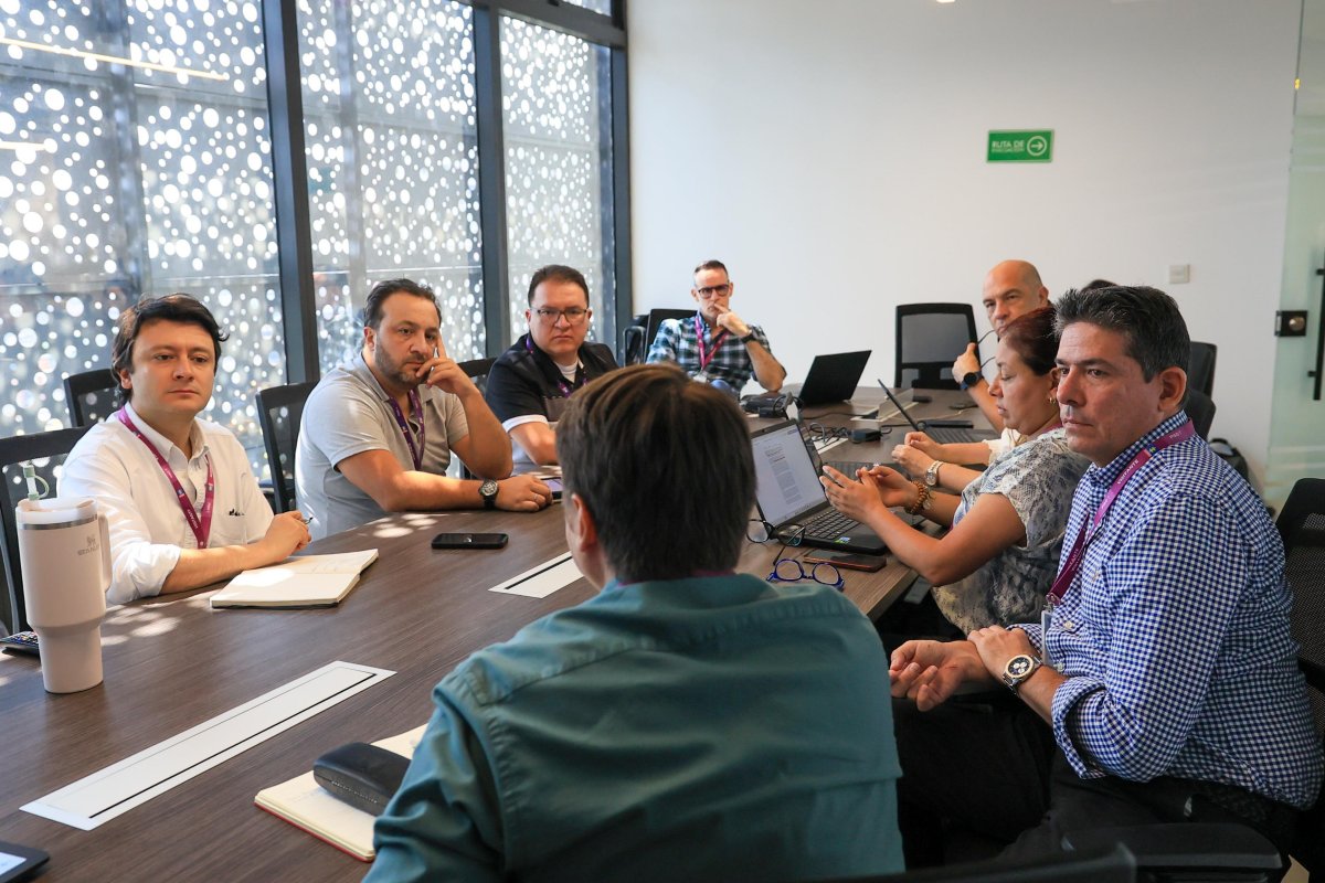 Grupo de personas en un reunión alrededor de una mesa.